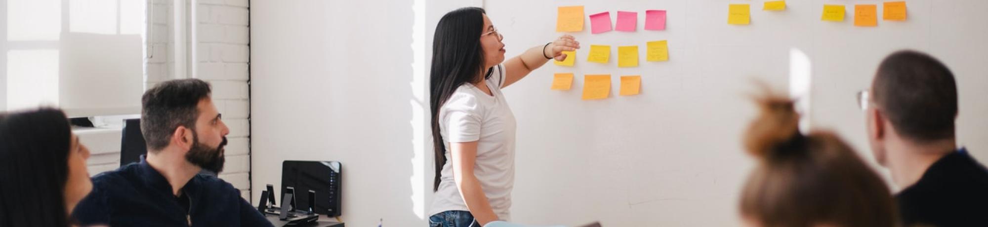 woman placing a sticky note on a board